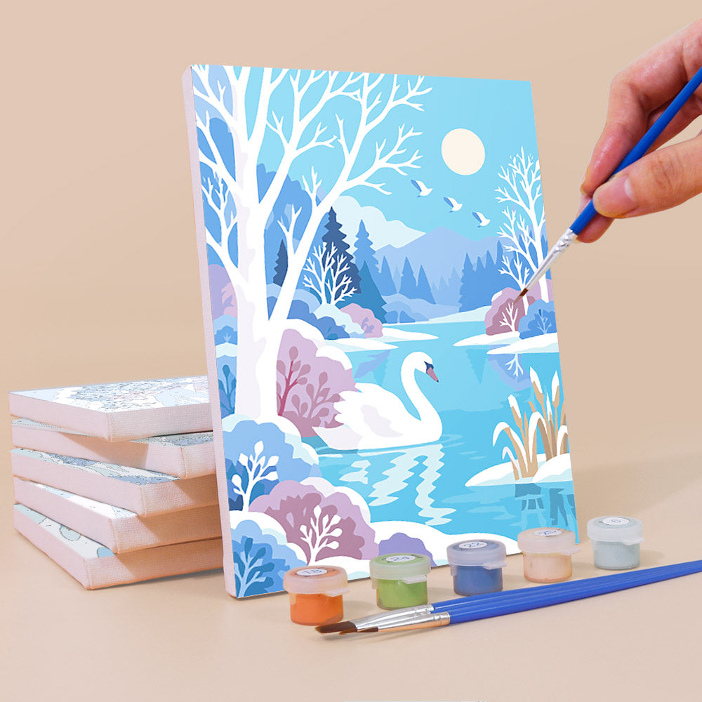 Painting a Winter Wonderland mini canvas propped up beside numbered acrylic paints