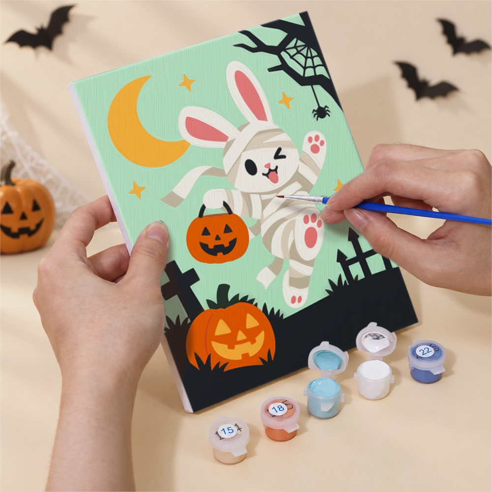 Hand holding a Woodland Costume Party mini canvas while painting the details