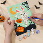 Hand holding a Woodland Costume Party mini canvas while painting the details