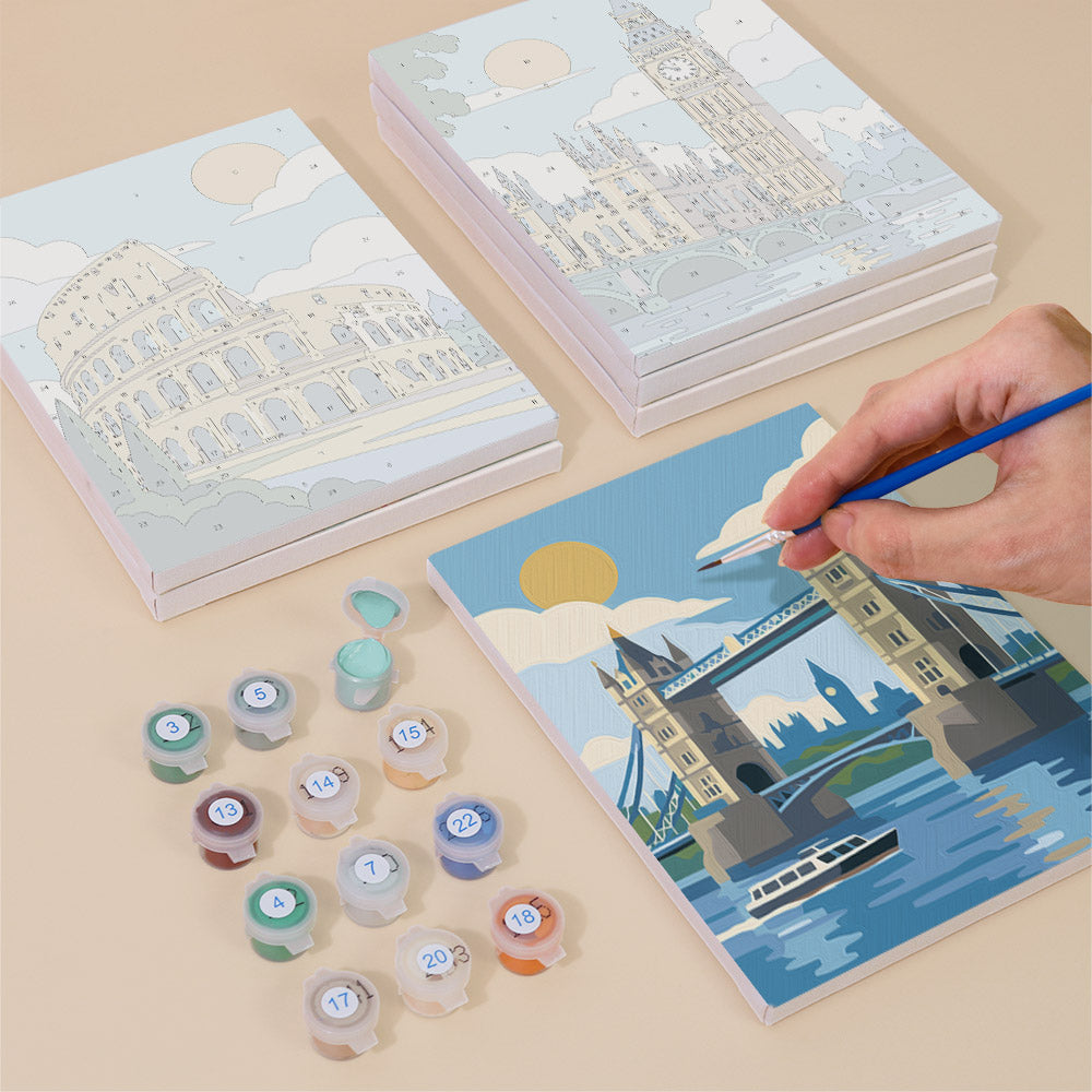 Painting one of the World Landmarks designs next to a stack of mini canvases
