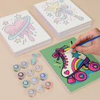 Painting one of the Y2K Doodles designs next to a stack of mini canvases