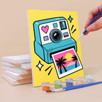 Painting a Y2K Doodles mini canvas propped up beside numbered acrylic paints